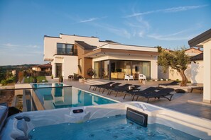 Une maison moderne dotée d’une piscine, d’un espace salon extérieur et d’un jacuzzi.