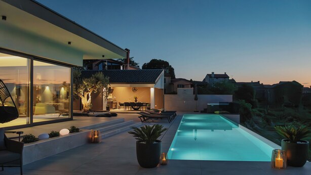 A modern outdoor pool area with a glass-enclosed patio, lounge seating, and potted plants. - Villa Kim Momjan With Pool and Spa (Buje)
