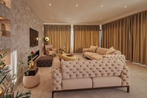 Een moderne woonkamer met een grote beige bank, een ronde salontafel en een flatscreen televisie aan de muur.