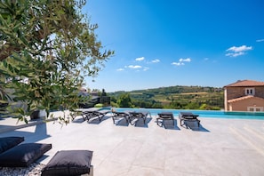 Une terrasse sur le toit avec une piscine, des chaises longues et une vue sur la campagne.
