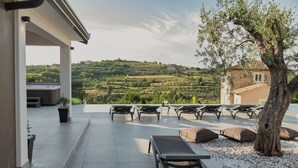 A terrace with sun loungers, a tree, and a view of a hilly landscape. - Villa Kim Momjan With Pool and Spa (Buje)