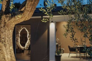 Un interior moderno con una pared de piedra, una zona de comedor con sillas y una mesa, y una planta en maceta.
