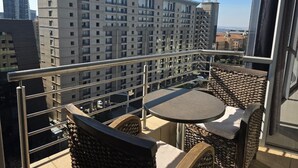 Un balcón con una mesa y sillas, con vistas a un paisaje urbano de edificios altos.