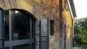 A brick building with large windows and a metal door. - Podere Montevalle's Clubhouse (Provincia di Piacenza)