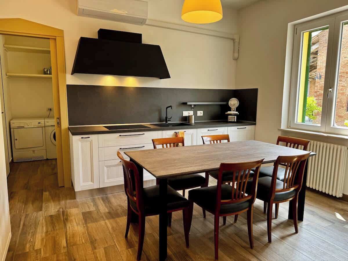Une cuisine moderne avec des meubles blancs, une table à manger en bois et des chaises.