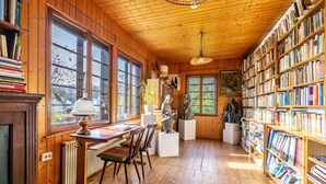 A wooden-paneled room with a wooden desk, chairs, a radiator, and bookshelves filled with books. - Holiday Home 'Hueseken' with Shared Garden and Wi-Fi (Finnentrop)