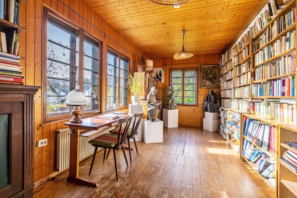 A wooden-paneled room with a wooden desk, chairs, a radiator, and bookshelves filled with books.