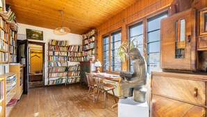 A wooden interior with bookshelves, a dining area, and a large window. - Holiday Home 'Hueseken' with Shared Garden and Wi-Fi (Finnentrop)