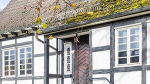 A traditional half-timbered house with a stone foundation, a wooden door, and multiple windows. - Holiday Home 'Hueseken' with Shared Garden and Wi-Fi (Finnentrop)