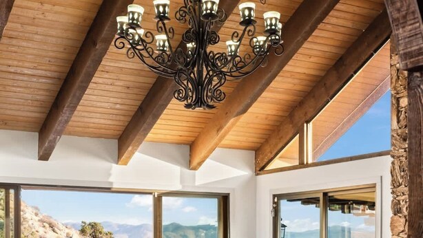 Un salon spacieux avec un plafond haut, de grandes fenêtres et une vue sur l’extérieur.