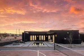 Un bâtiment moderne doté d’une piscine, d’un espace extérieur aménagé et surplombant un paysage désertique.