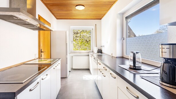 A modern kitchen with a wooden ceiling, a window with a view, and a coffee maker on the counter. - Guesthouse with Shared Garden and Wi-Fi (Finnentrop)