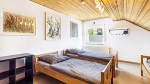 A room with two wooden beds, a black shelf, and artwork on the walls. - Guesthouse with Shared Garden and Wi-Fi (Finnentrop)