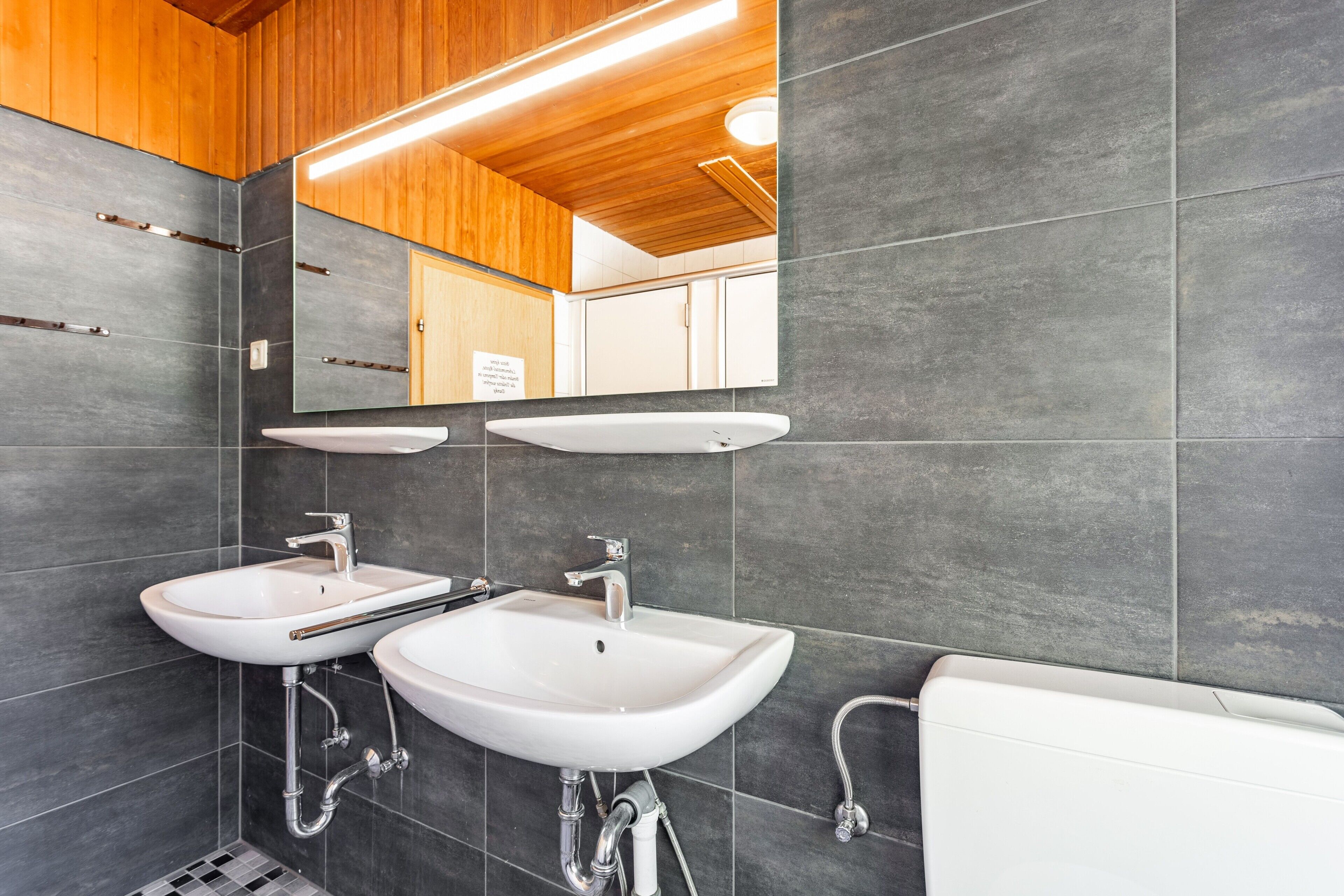 Ein modernes Badezimmer mit zwei Waschbecken, einem Spiegel und einer Toilette.