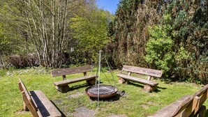 A picnic area with benches and a fire pit surrounded by greenery. - Guesthouse with Shared Garden and Wi-Fi (Finnentrop)