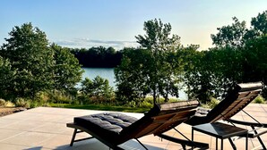 Two lounge chairs facing a lake with trees in the background. - Amazing villa with swimming pool next to the lake. (Wrzeszewo)