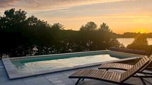 A swimming pool with a view of the sunset over a body of water, surrounded by trees. - Amazing villa with swimming pool next to the lake. (Wrzeszewo)