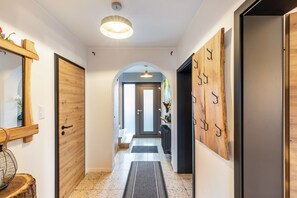 A hallway with a wooden door, a mirror, a hanging light fixture, and a wall-mounted coat rack. - Holiday Home 'Liebe' with Shared Garden, Balcony and Wi-Fi (Seesbach)