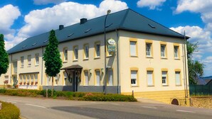 Ein zweistöckiges Gebäude mit flachem Dach, zahlreichen Fenstern und einem Schild, das es als Hotel kennzeichnet.