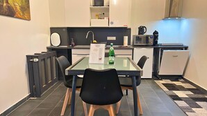 Eine kompakte Küche mit Esstisch, Stühlen, Mikrowelle, Wasserkocher und Kühlschrank.