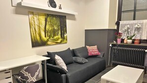 Ein modernes Wohnzimmer mit einem grauen Sofa, einem weißen Schreibtisch und einer Heizung.