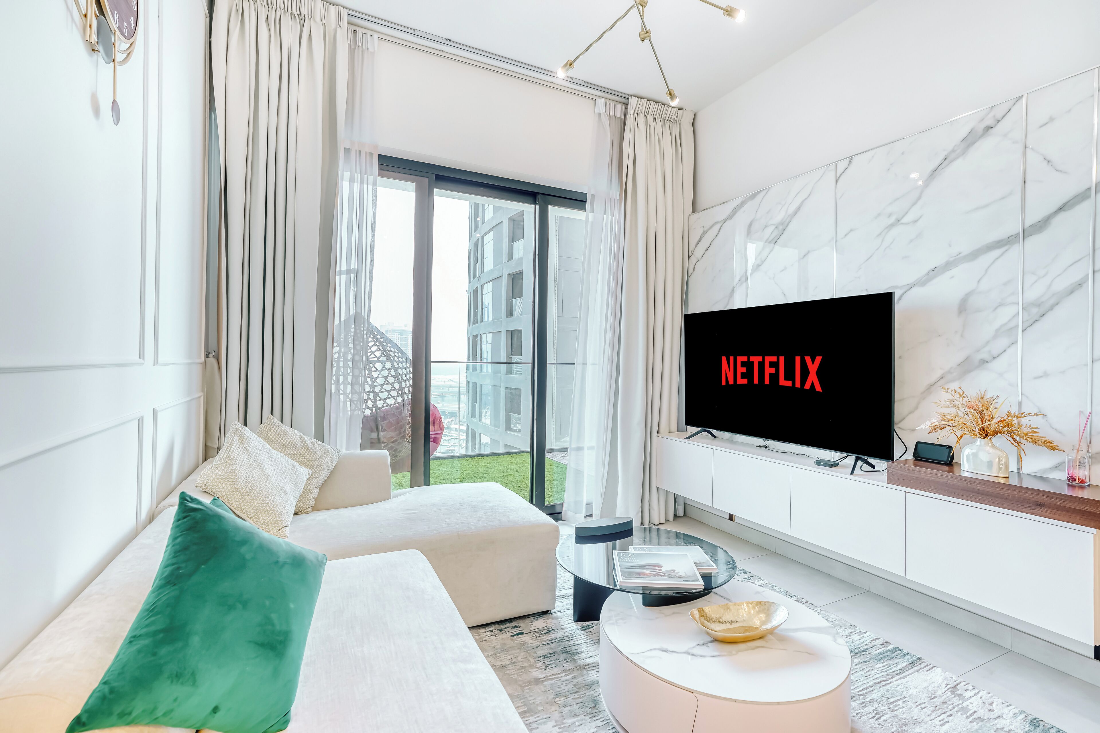 Ein modernes Wohnzimmer mit einer Couch, einem Couchtisch und einem Fernseher, der "NETFLIX" anzeigt.