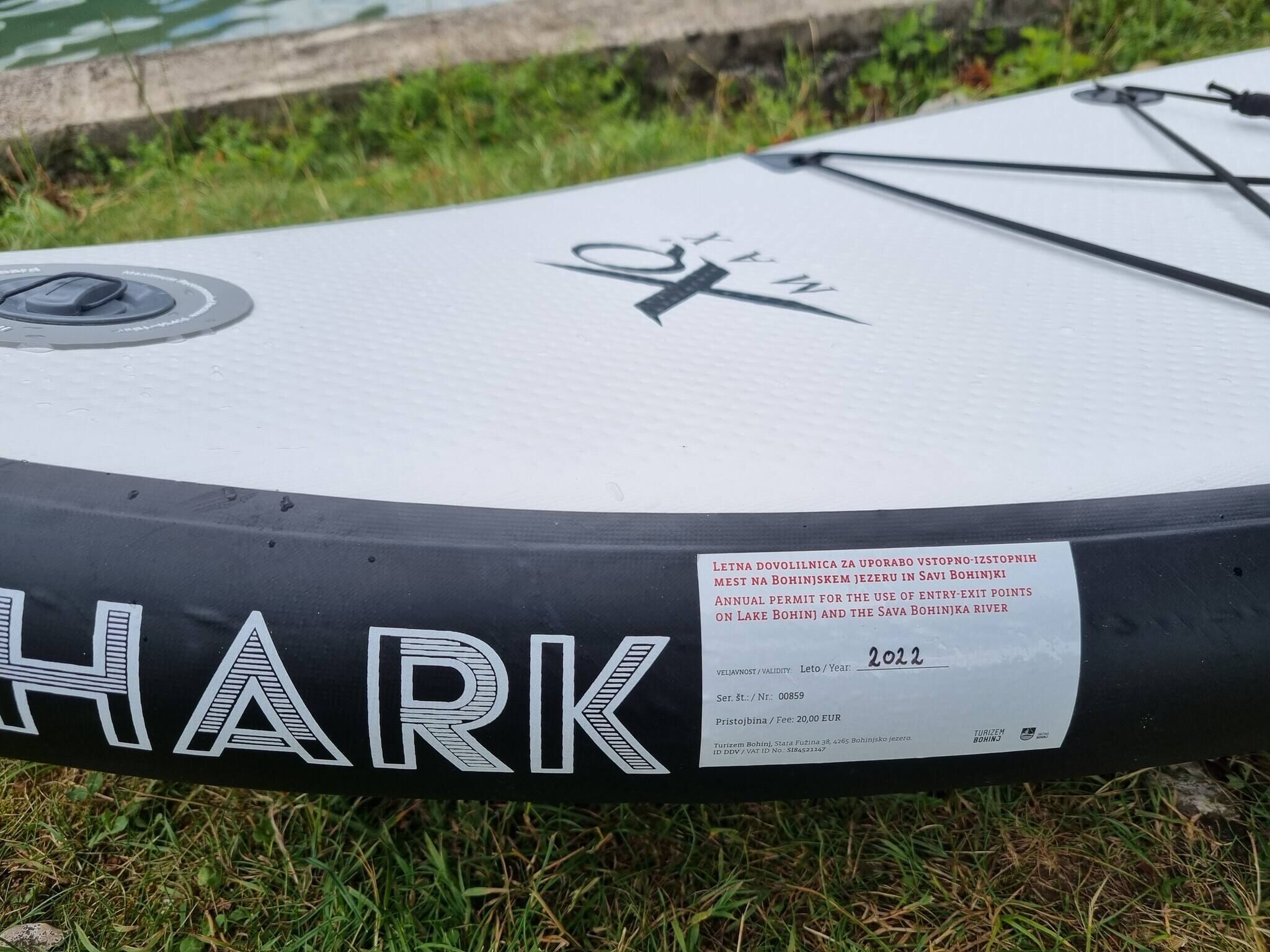 A boat with the word 'HARK' on its side, a navigation symbol, and a permit sticker for Lake Bohinj.