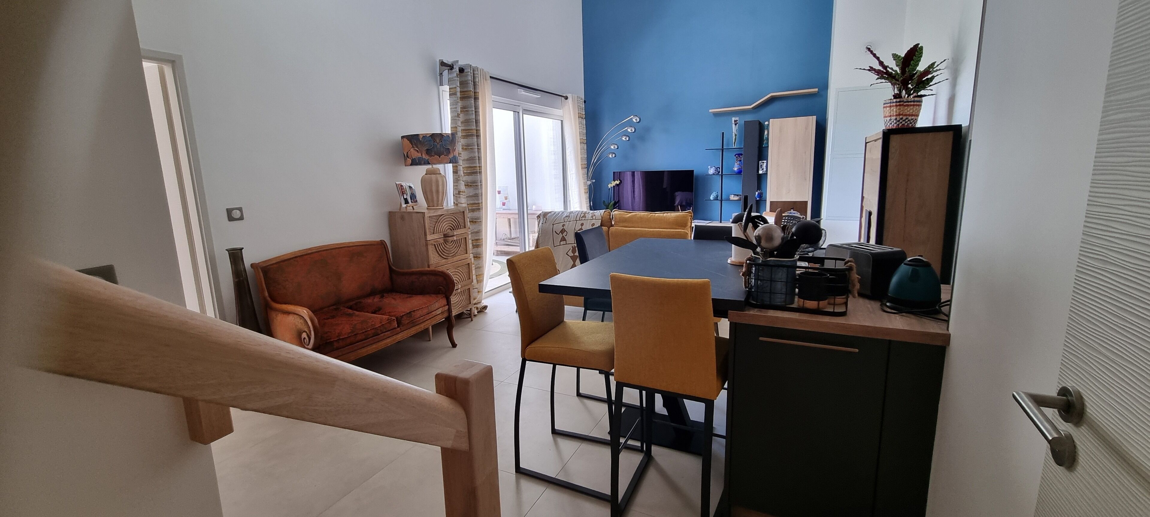 A dining area with a table and chairs, a sofa, and a kitchen counter with appliances.