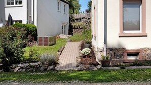 Una proprietà residenziale con un vialetto lastricato, una scala in legno e un giardino con diverse piante.