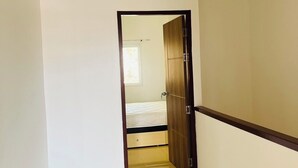 Un couloir étroit avec une porte en bois donnant sur une chambre à coucher.