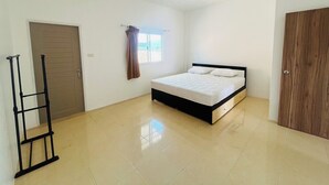 Une chambre à coucher avec un lit, une fenêtre avec des rideaux, une porte et une armoire.