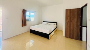 Une chambre à coucher avec un lit, une fenêtre avec des rideaux, une porte en bois et un sol carrelé.