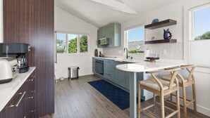 Eine moderne Küche mit einer zentralen Kochinsel, Holzschränken und Blick ins Freie.