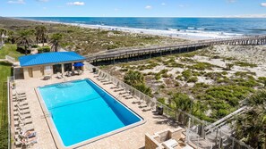 Ein Poolbereich mit Liegestühlen, einem Pool und Blick auf den Strand.