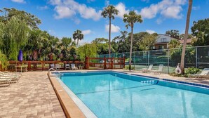 Ein rechteckiger Swimmingpool mit Holzterrasse und Liegestühlen.