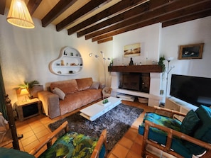 Una sala de estar con sofá, mesa de centro, sillas, chimenea y televisor.