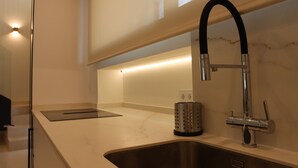 A modern kitchen with a stainless steel sink, a black faucet, and a marble countertop. - La Tajuela Casa Rural (Bohonal de Ibor)
