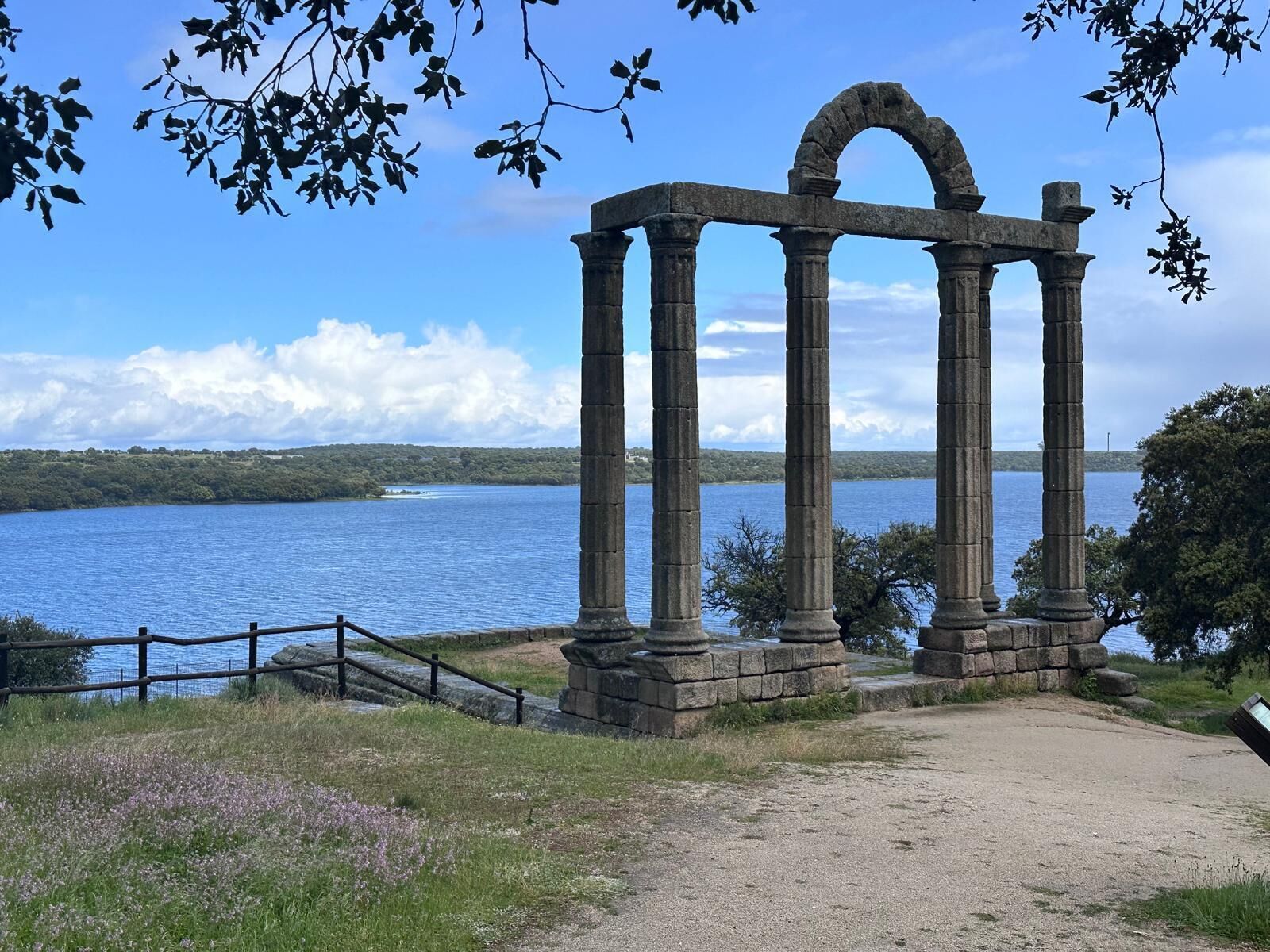A stone structure with columns by a lake.
