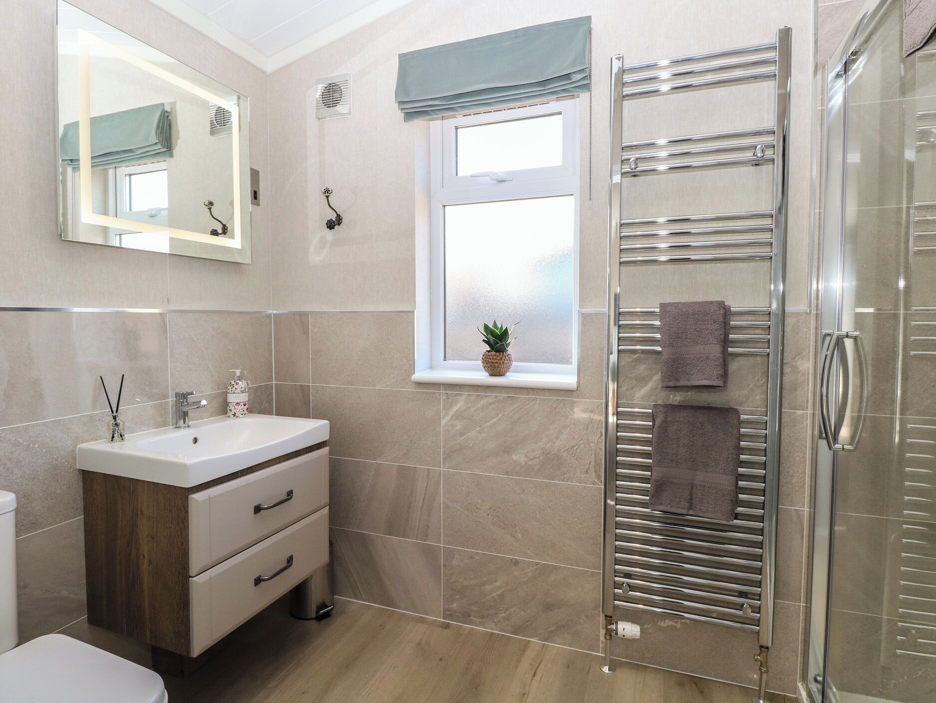 Een moderne badkamer met een glazen douchecabine, een wastafelmeubel met een wastafel en een raam met uitzicht.