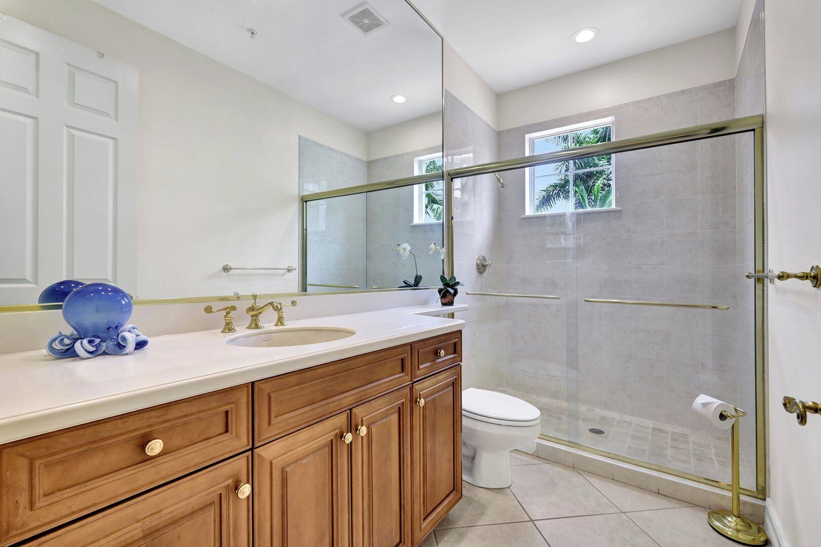 A modern bathroom with a glass-enclosed shower, a white sink, and wooden cabinets.
