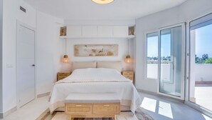 A bedroom with a bed, bedside tables, a ceiling light, a window, and a view of the outside.