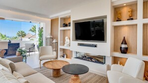 A modern living room with a flat-screen TV, comfortable seating, and a fireplace.