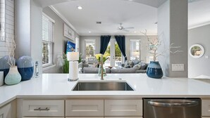 A modern kitchen with a white countertop, stainless steel sink, and a built-in dishwasher. - Tropical Paradise: 4BR Island Home w/ Pool & Bay Views (Anna Maria)