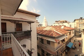 A multi-story building with balconies, a satellite dish, and a traditional tower in the background. - 2BR in Stone Town – Near Ferry Terminal, Museums & Cultural Sights (Stone Town)