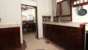 A kitchen with wooden cabinets, a countertop, and a window with a curtain. - 2BR in Stone Town – Near Ferry Terminal, Museums & Cultural Sights (Stone Town)