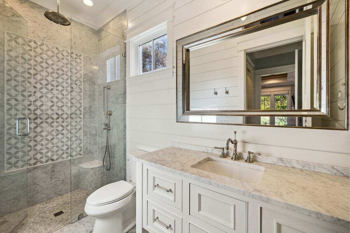 A bathroom with a shower, toilet, and vanity with a large mirror.