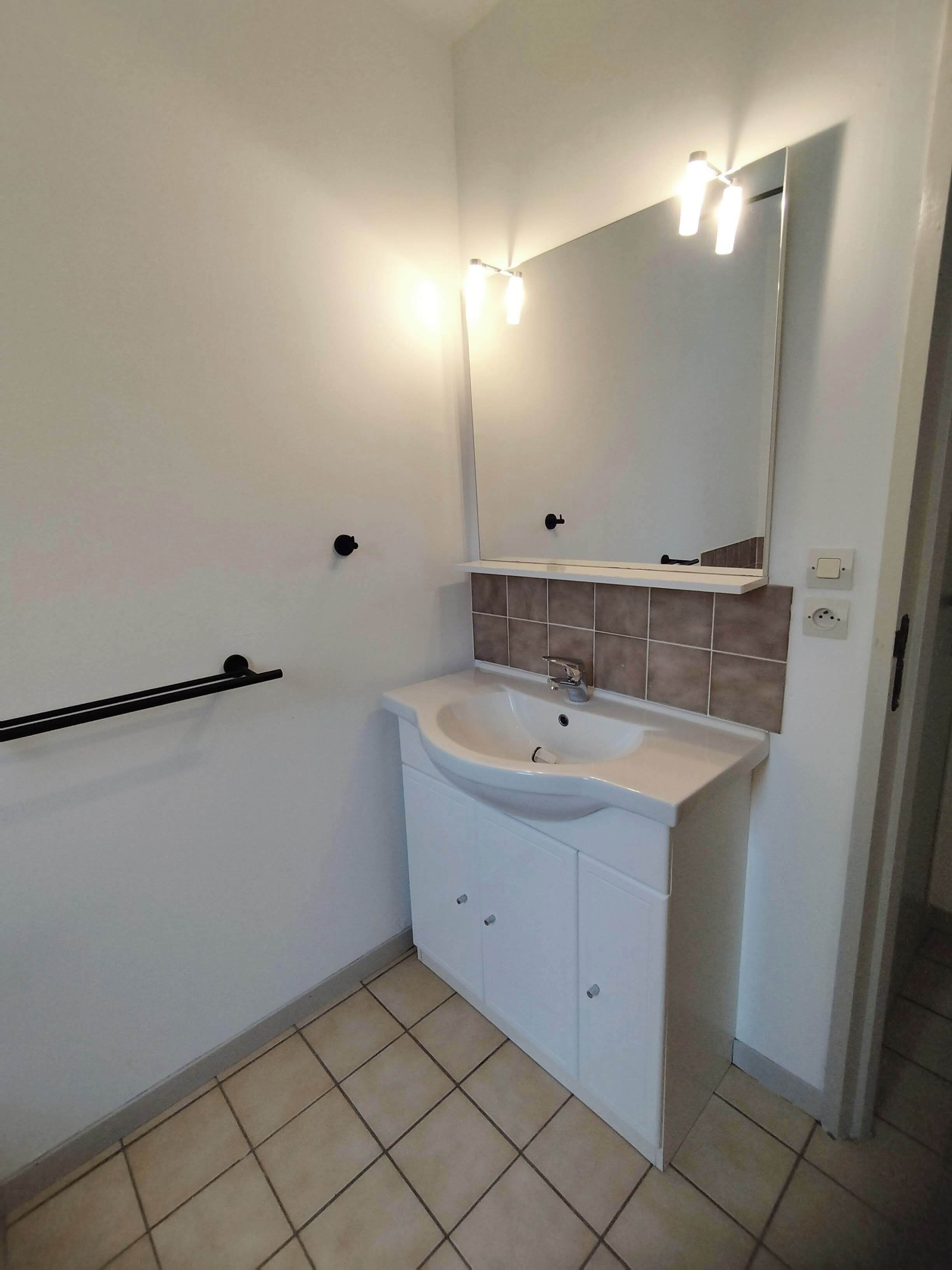Ein Badezimmer mit Waschbecken, Spiegel und Handtuchhalter.