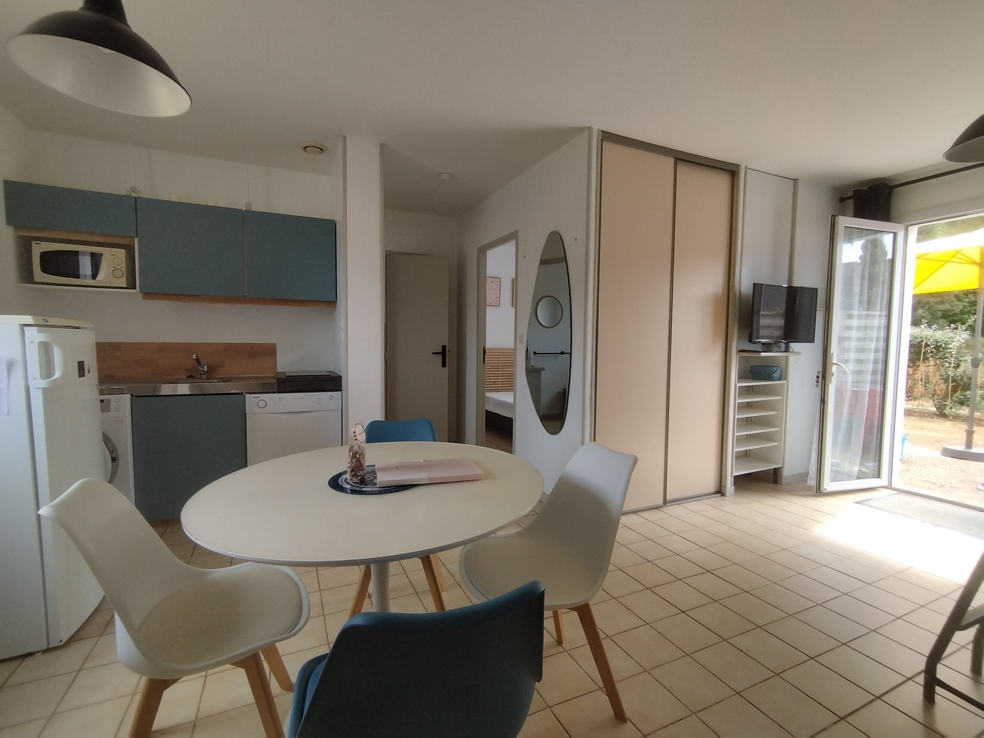 Un espacio habitable compacto con cocina, comedor y un televisor pequeño.