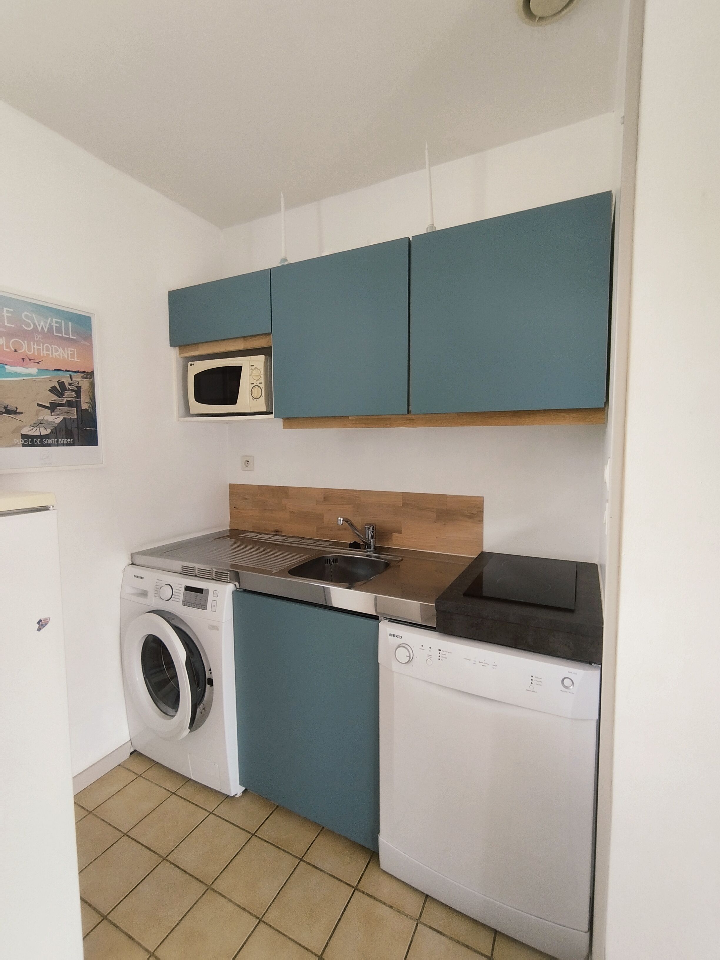 A compact kitchen with a washing machine, a microwave, and a sink.