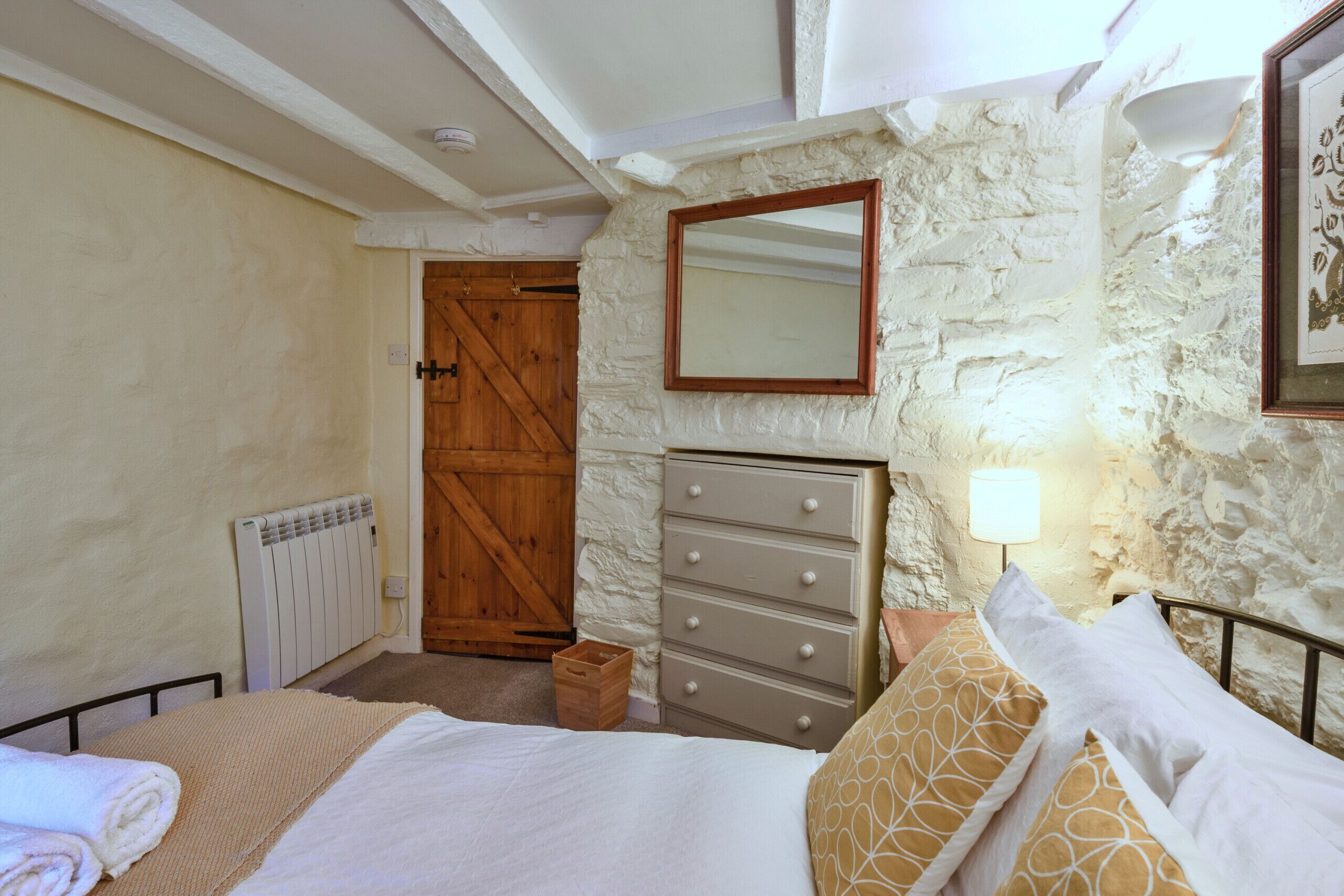 Une chambre à coucher avec un lit, une commode et une porte en bois.